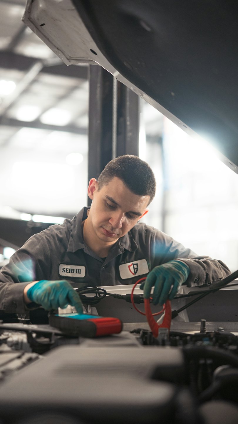 Mechanic using diagnostic tool on car engine in garage.